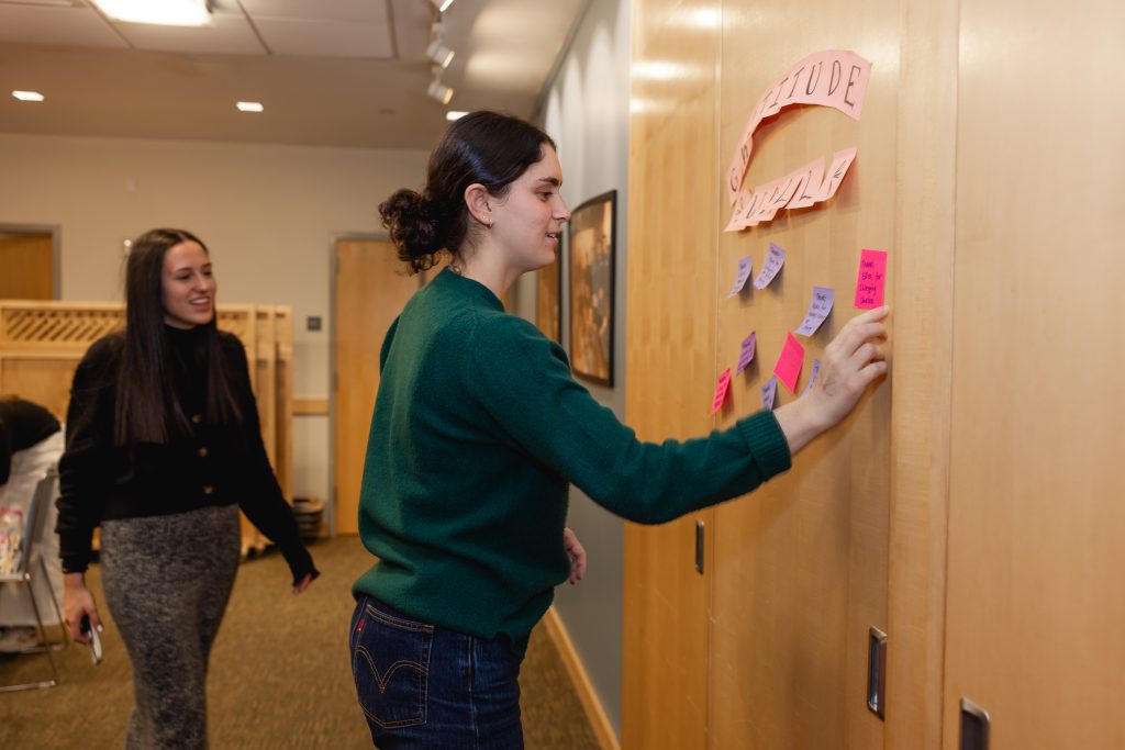 Columbia University and Barnard Students placing messages of gratitude on a gratitude wall during the Friendsgiving dinner