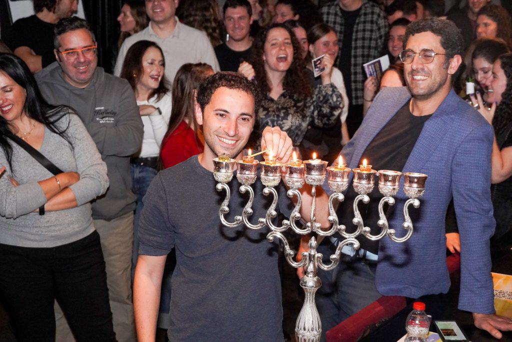 Rabbi Joe Wolfson lighting Chanukah candles with members of the Tel Aviv JLIC community at their annual Chanukah party.